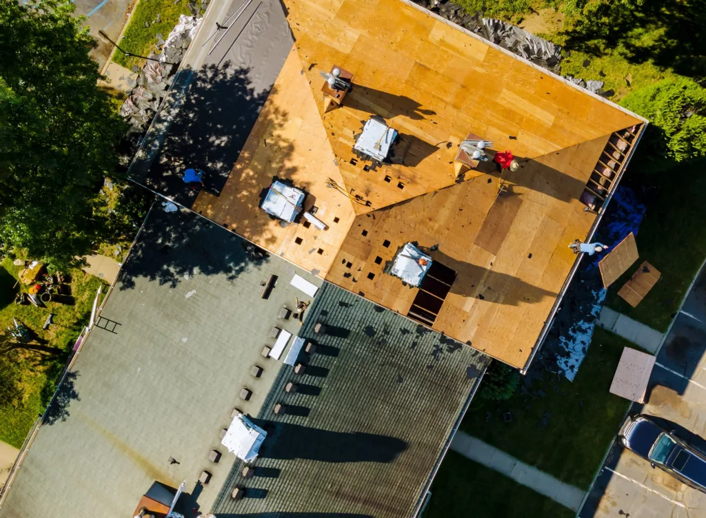 Top-down aerial view of a roof replacement with crew members on the deck